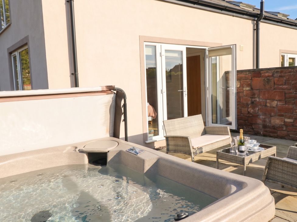 An outdoor area with a hot tub and seating at Coney Garth Retreat in Beckermet
