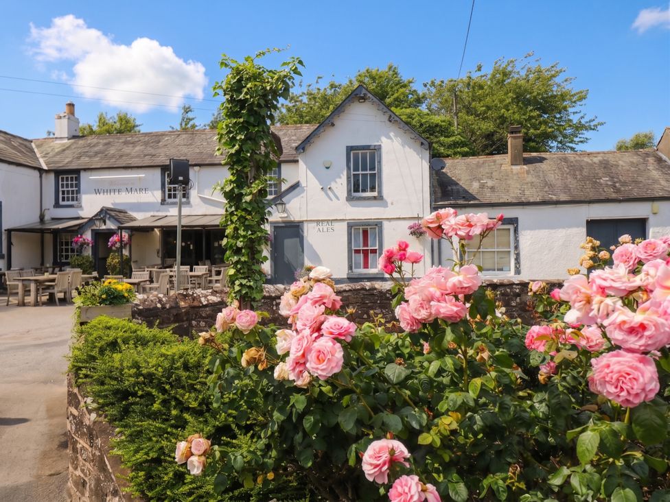 An exterior view of a pub with seating outside at Coney Garth Retreat in Beckermet