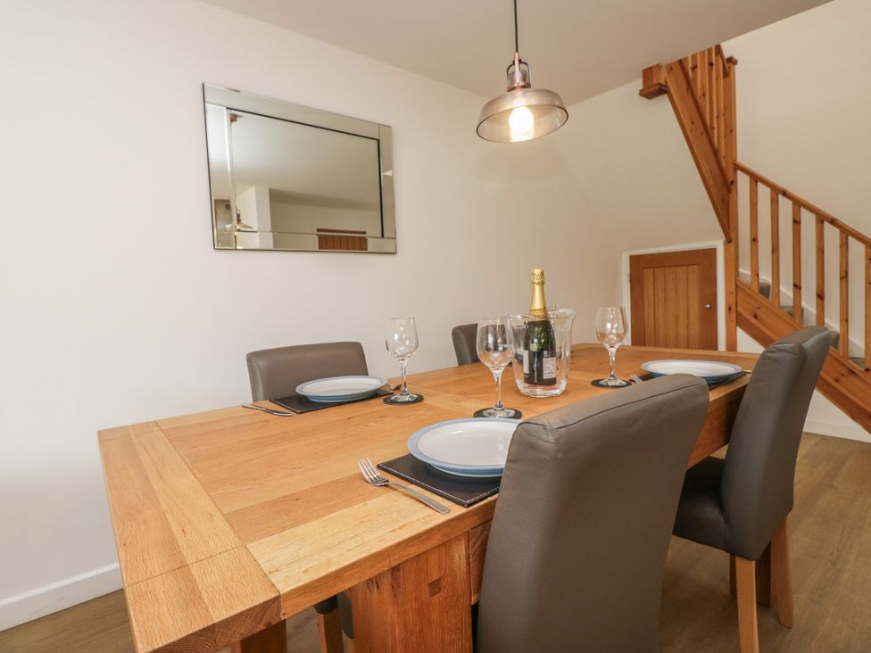 A dining room with a table set and a staircase at Coney Garth Cottage in Beckermet