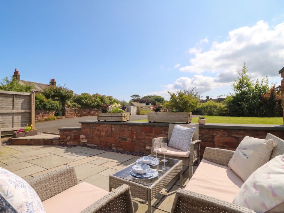 A garden with outdoor seating and tableware at Coney Garth Cottage in Beckermet