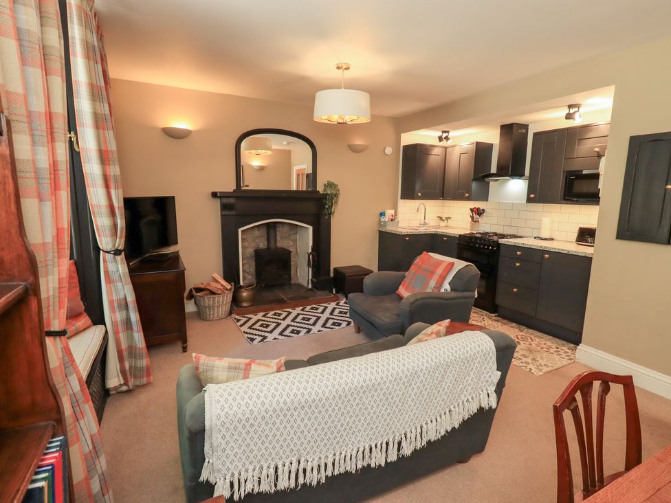 A living room with a fireplace and kitchen in The Cells Ingleton