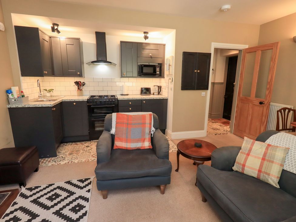A living room with a kitchen area and seating at The Cells in Ingleton