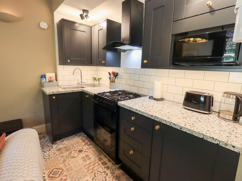 A kitchen with cabinets, sink, stove, microwave and toaster at The Cells in Ingleton