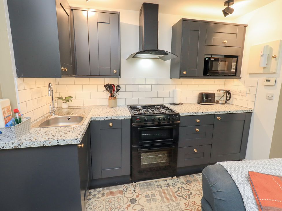 A kitchen with stove, sink, microwave, and cabinets at The Cells Ingleton