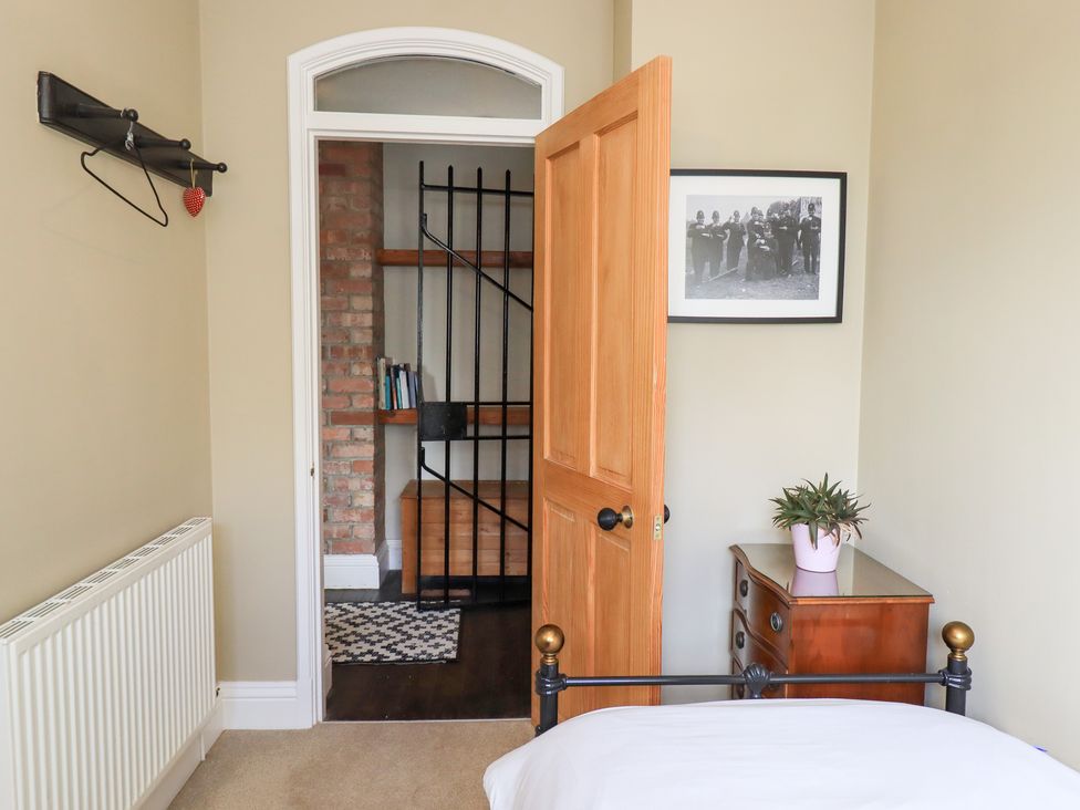 A bedroom with a door leading to a shelf area at The Cells in Ingleton