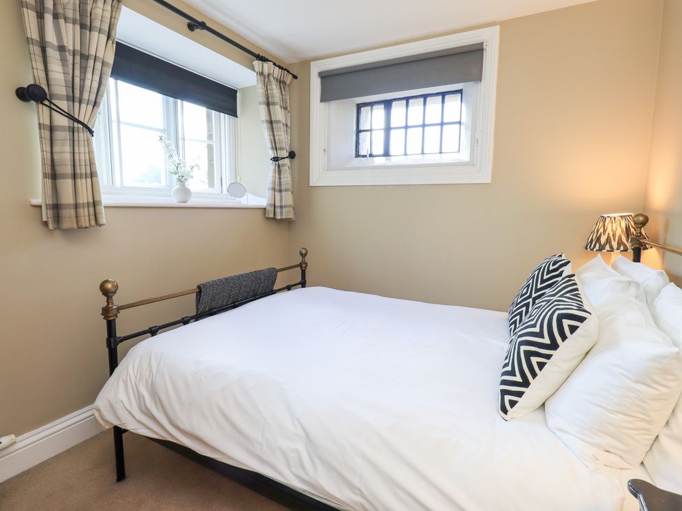 A bedroom with a bed and windows at The Cells in Ingleton