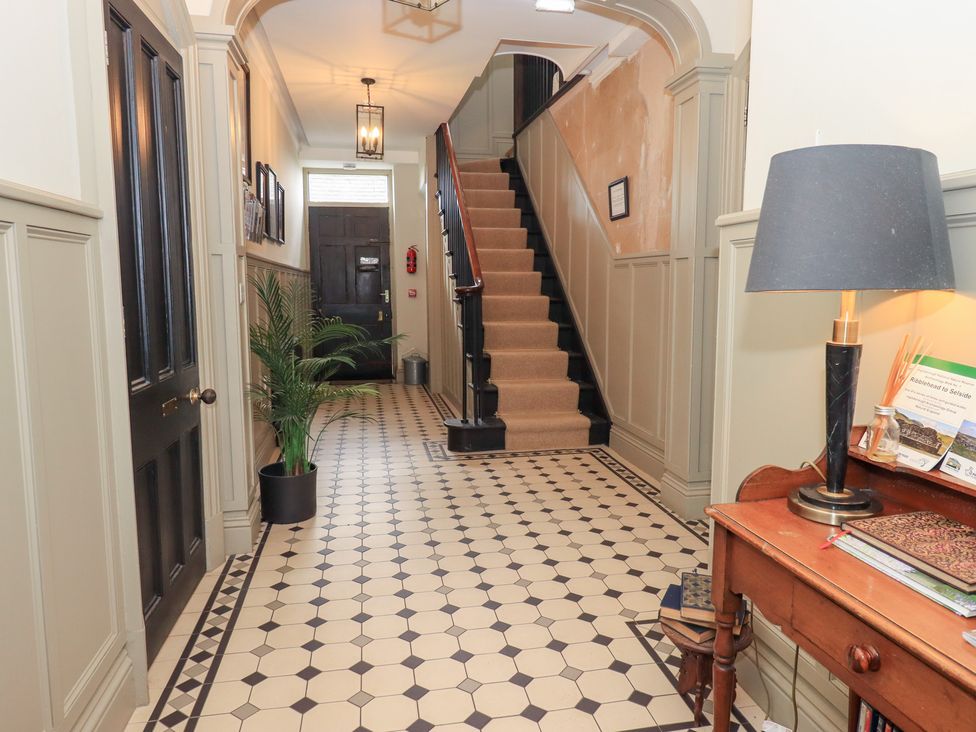 A hallway with a staircase and a desk at The Cells in Ingleton