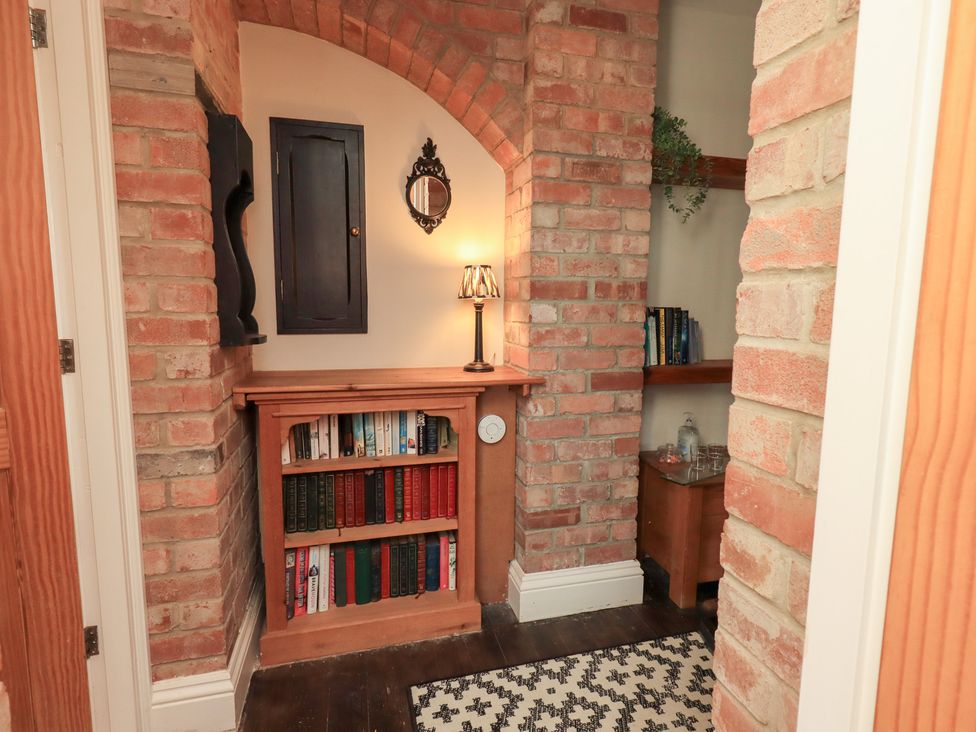 A reading nook with a bookshelf and lamp at The Cells in Ingleton