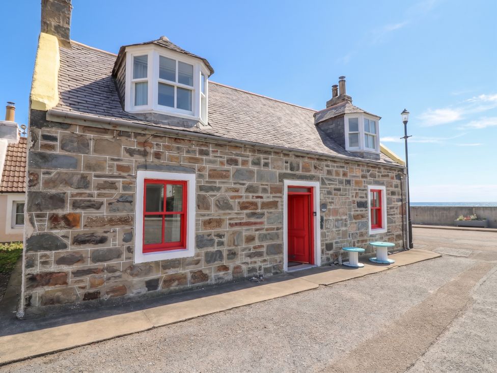 A stone house with red door and windows at Dookers Hoose Cullen