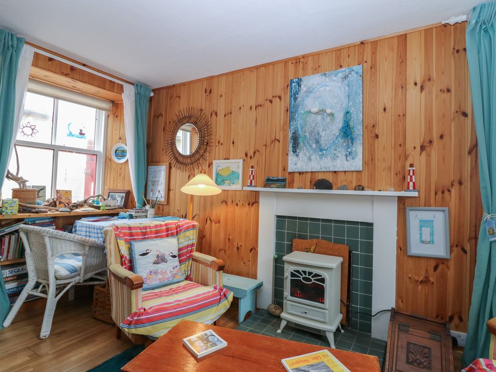 A living room with a fireplace and bookshelf at Dookers Hoose Cullen