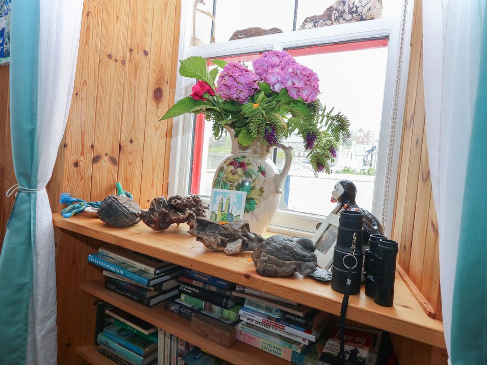 A sitting room with a window and decorative items at Dookers' Hoose in Cullen