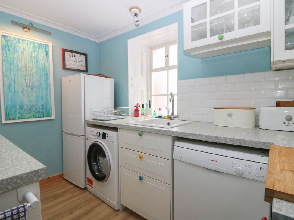 A kitchen with a refrigerator, washing machine, and sink at Dookers Hoose Cullen