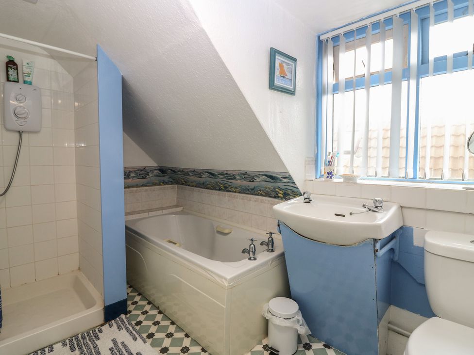 A bathroom with a bathtub, shower, sink and toilet at Dookers' Hoose in Cullen