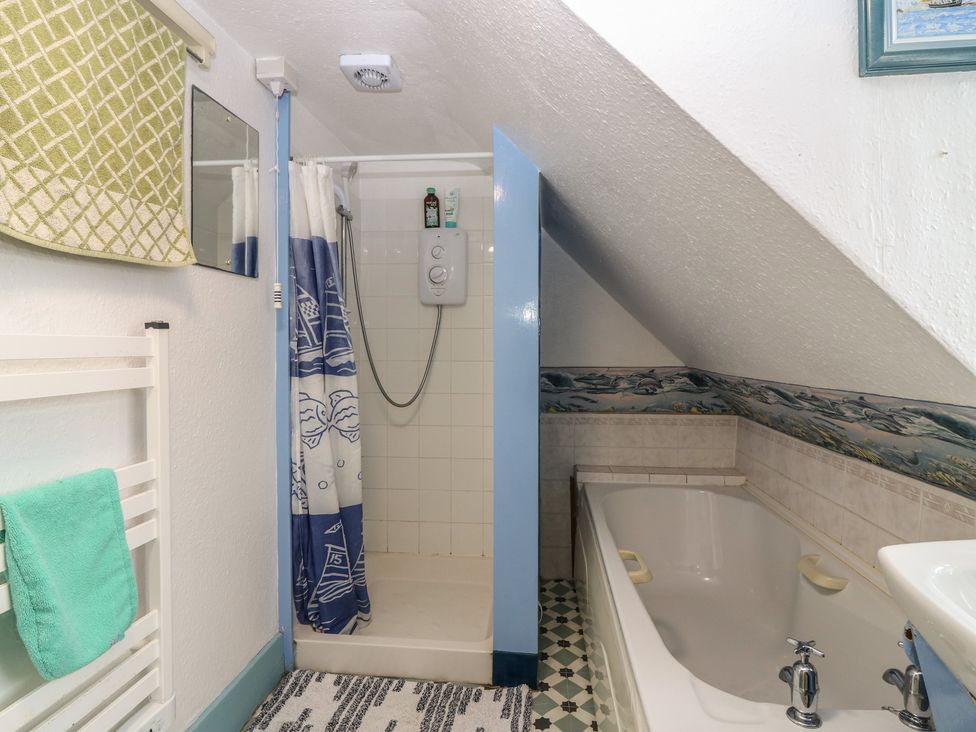 A bathroom with a shower, bathtub, and towel rail at Dookers Hoose in Cullen