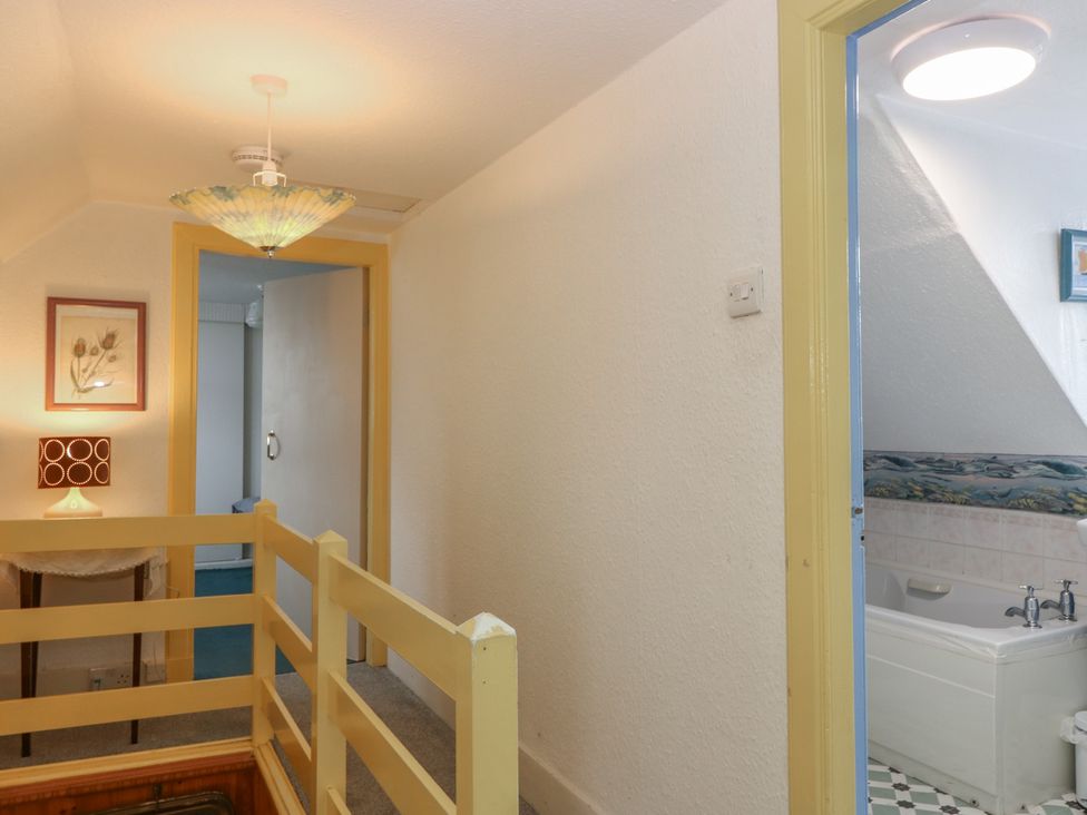 A hallway with a lamp and a doorway leading to a bathroom at Dookers' Hoose in Cullen