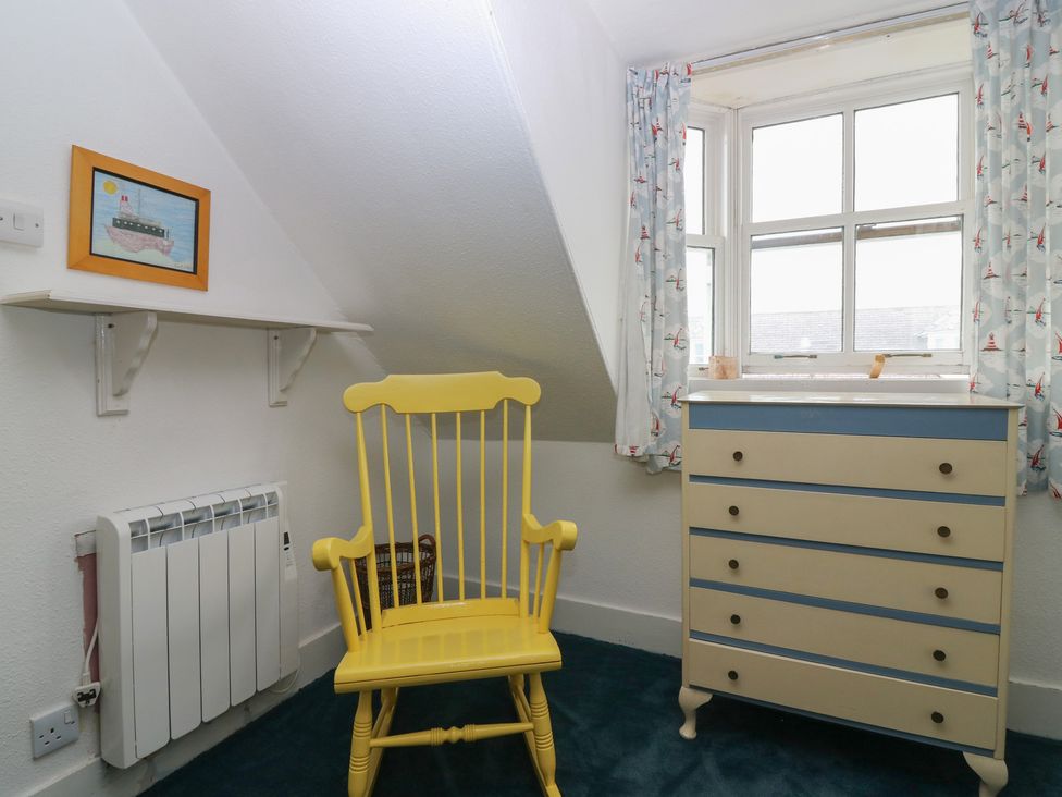 A bedroom with a yellow rocking chair and chest of drawers at Dookers Hoose in Cullen