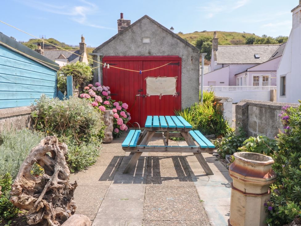 A garden with a picnic table and flowers at Dookers Hoose in Cullen