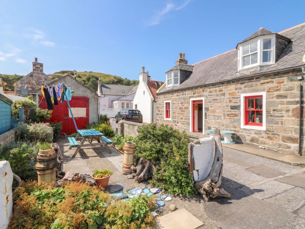 An outdoor area with a picnic table, clothesline, and plants at Dookers Hoose in Cullen