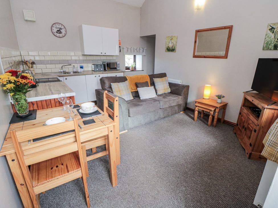 A living room with a sofa and kitchen area at Carters in Staintondale