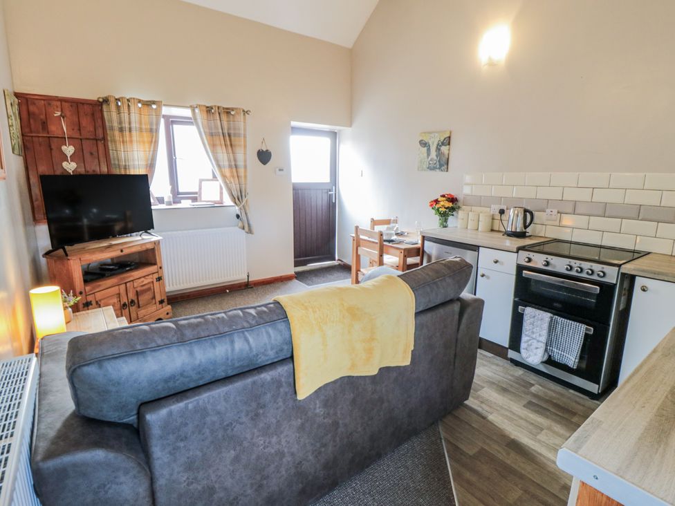A living room with a sofa and kitchen area at Carters in Staintondale
