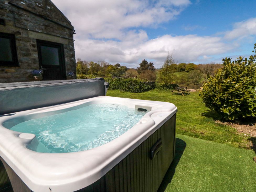 A hot tub with a view of trees and seating area at Carters Staintondale near Burniston