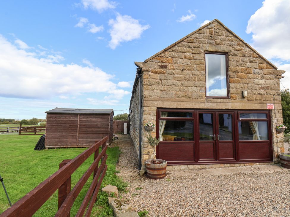 An outdoor area with a stone building and wooden shed at Hayloft in Staintondale