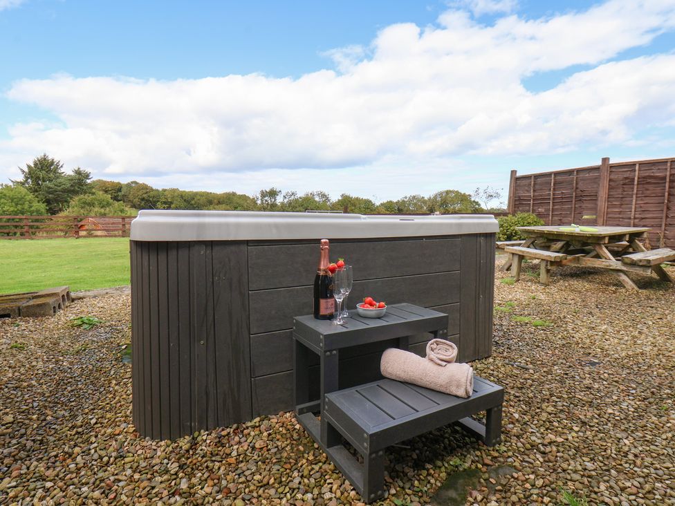 A hot tub with wine and glasses in the garden at Hayloft Staintondale