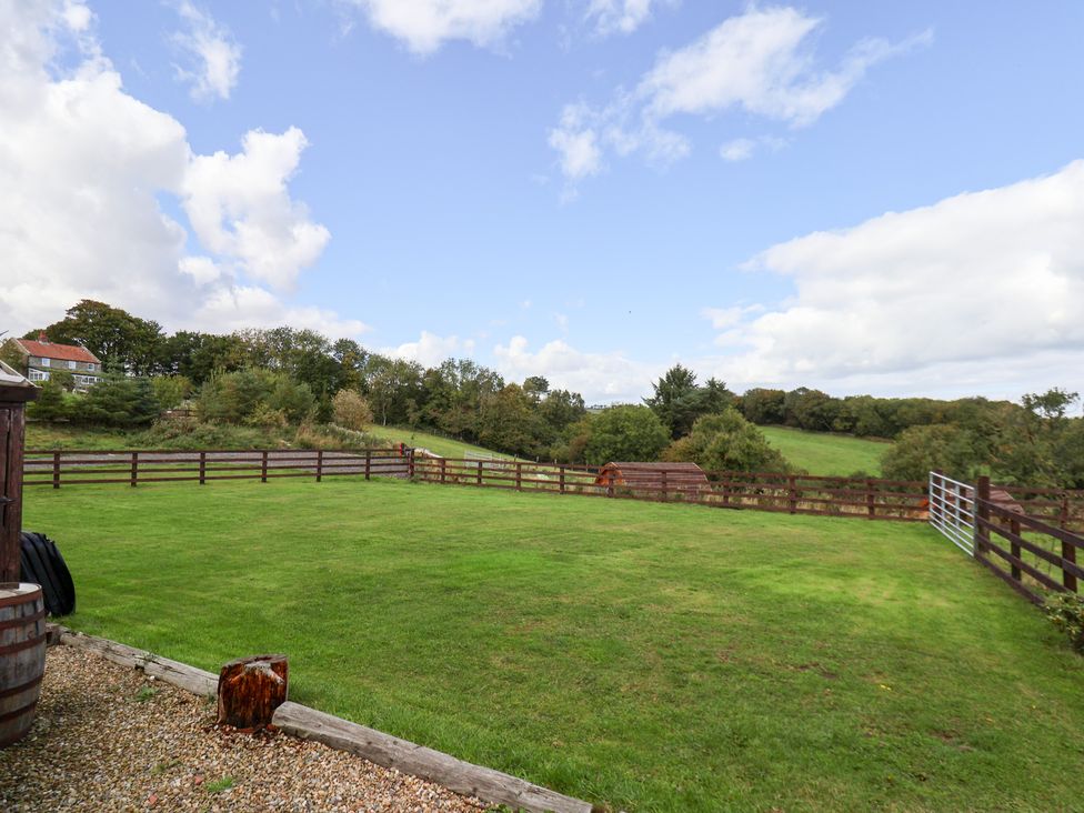 A garden area with a fence and trees at Hayloft in Staintondale