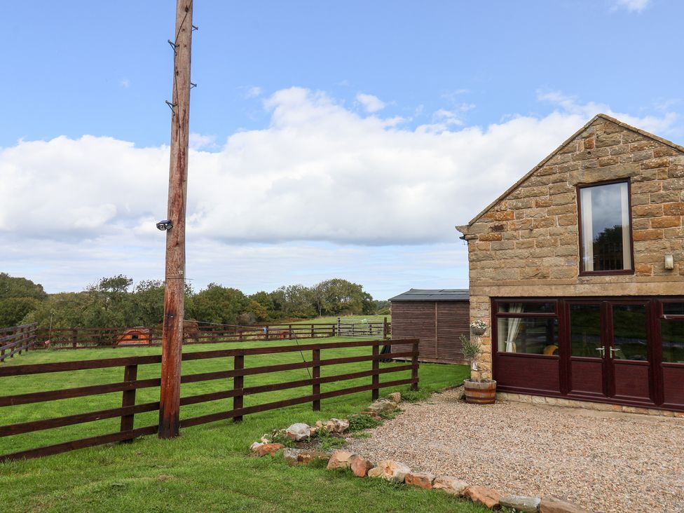 A building with a fenced area and gravel outside at Hayloft in Staintondale