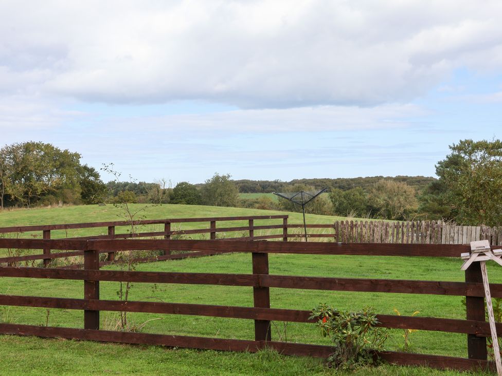 A view of a fenced field with trees and hills at Hayloft in Staintondale