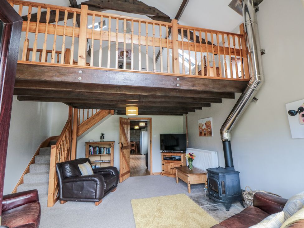 A living room with a staircase and television at Hayloft in Staintondale