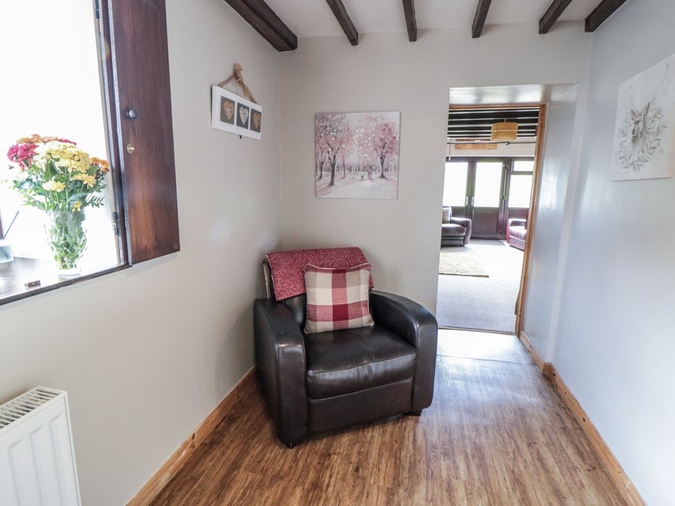 A living room with an armchair and flower vase at Hayloft in Staintondale
