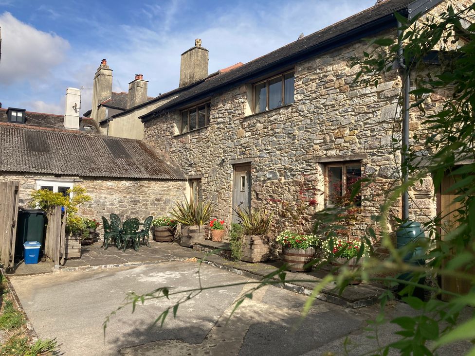 An outdoor area with stone building and patio furniture at Old Armoury Barn Ashburton