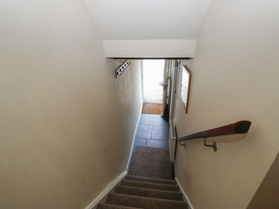 A staircase with a handrail leading to a door at Rose Cottage in Broughton-In-Furness