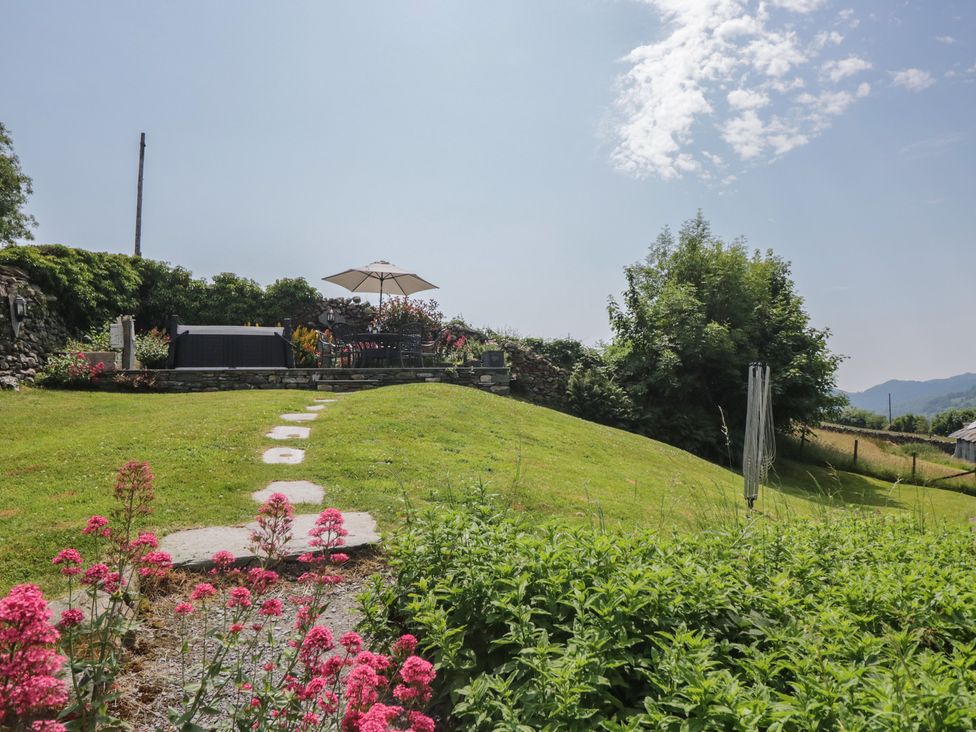 A garden with a seating area and flowers at Rose Cottage in Broughton-In-Furness