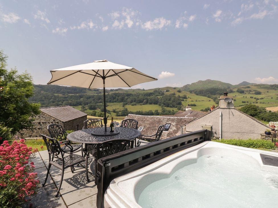 An outdoor area with a hot tub, table, and chairs at Rose Cottage in Broughton-In-Furness