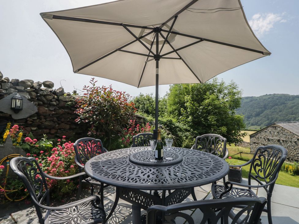 An outdoor seating area with a table and umbrella at Rose Cottage in Broughton-In-Furness