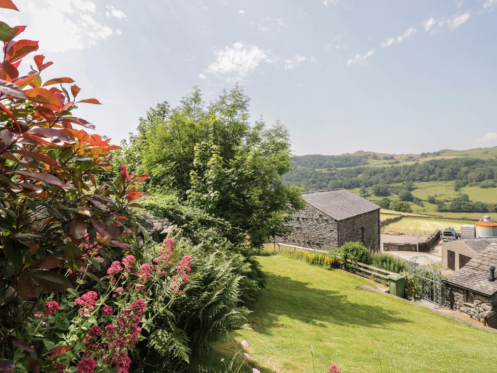 A garden with flowers and stone buildings at Rose Cottage Broughton-In-Furness