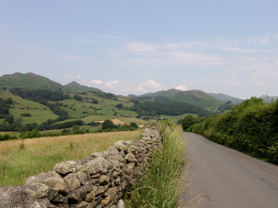 A landscape with fields and a stone wall alongside a road at Rose Cottage in Broughton-In-Furness