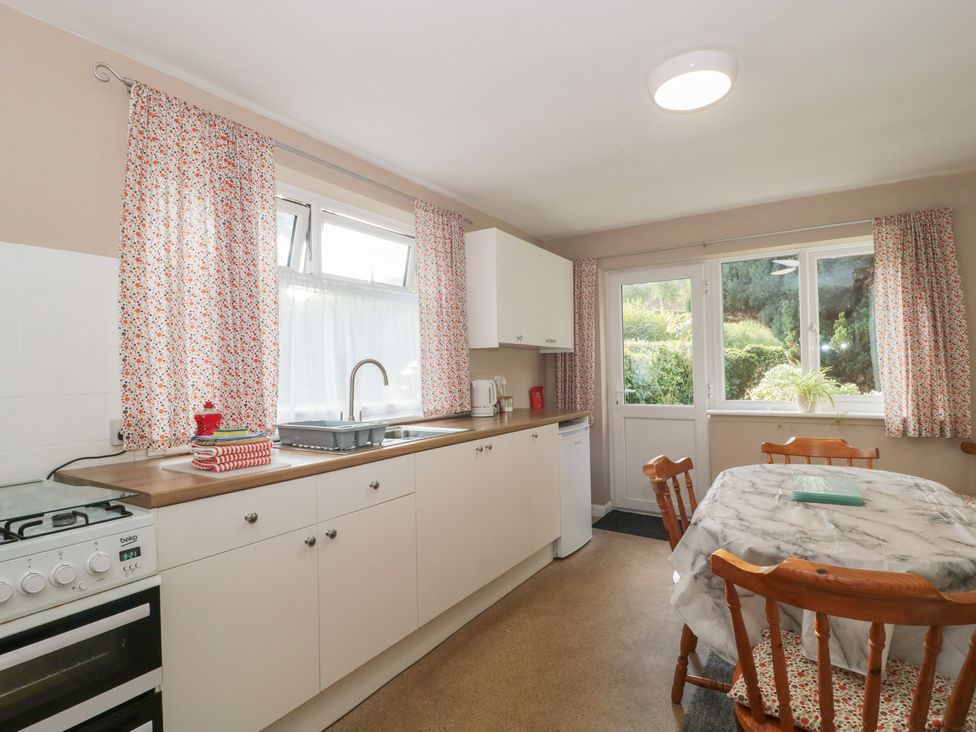 A kitchen with cabinets and a dining table at 1 Westcroft Cottage in King's Stanley