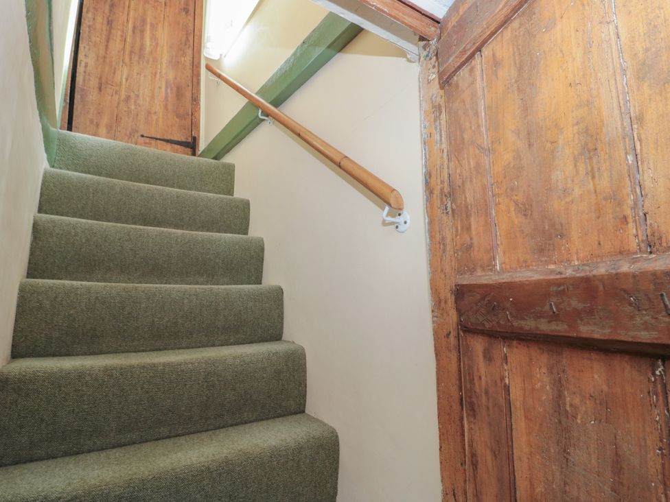 A staircase with carpet and a wooden door at 1 Westcroft Cottage in King's Stanley