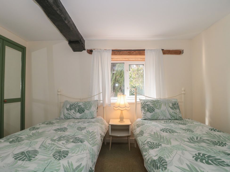 A bedroom with two beds and a window at 1 Westcroft Cottage in King's Stanley