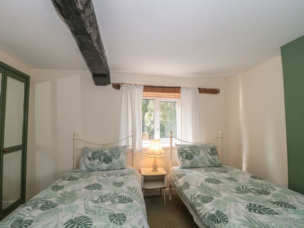 A bedroom with two single beds and a window at 1 Westcroft Cottage in King's Stanley
