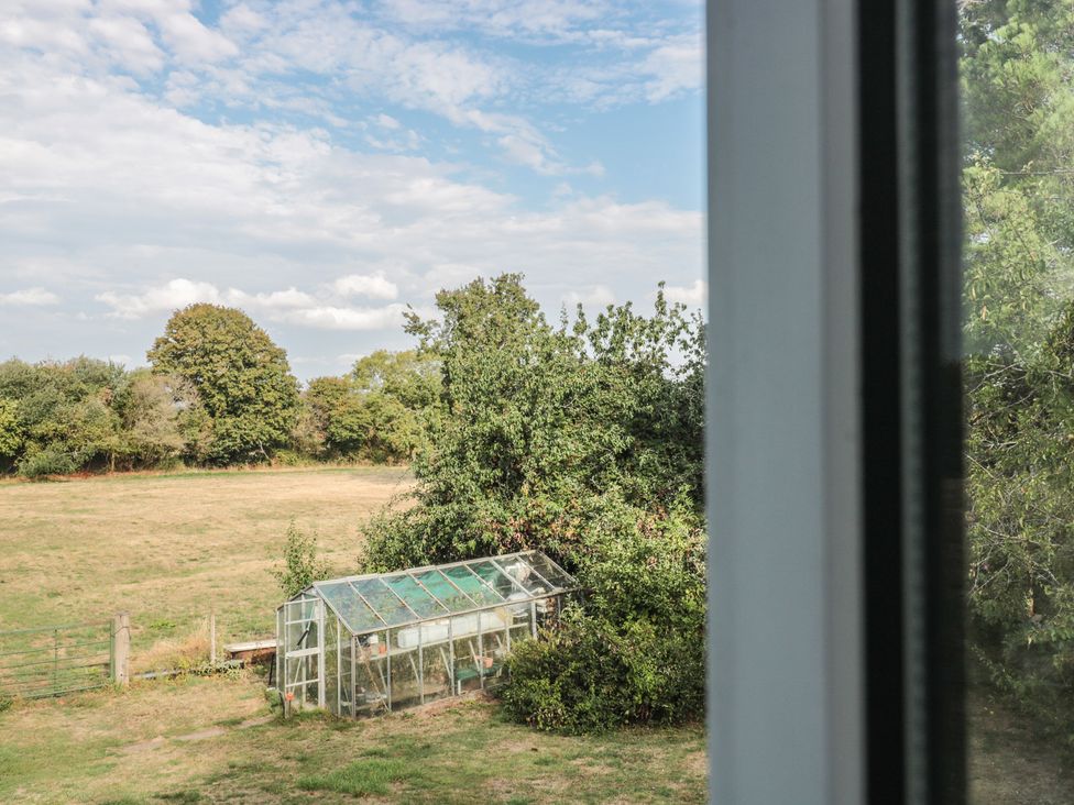 A view of a greenhouse and trees in an outdoor space at 1 Westcroft Cottage King's Stanley