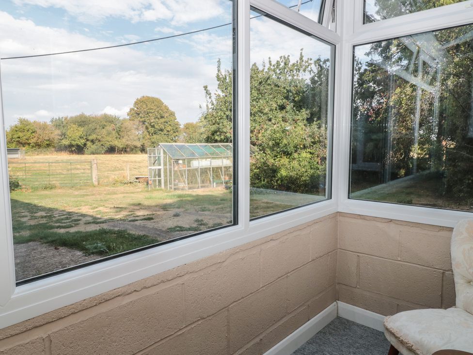 A conservatory with a view of a greenhouse and garden at 1 Westcroft Cottage King's Stanley
