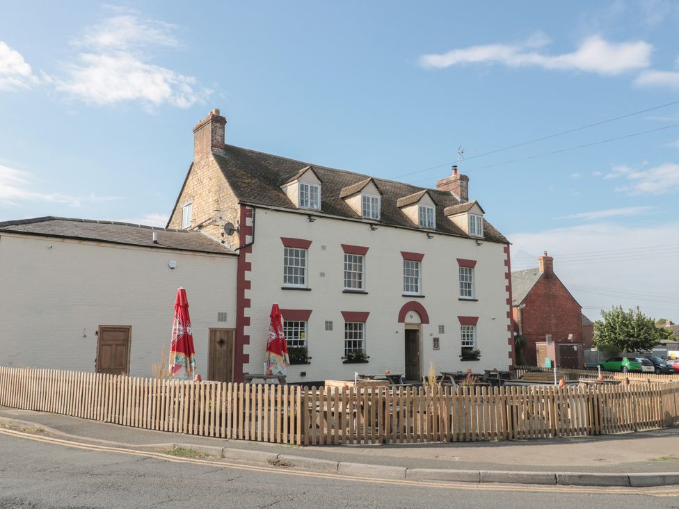 A building with a fence and patio umbrellas at 1 Westcroft Cottage in King's Stanley
