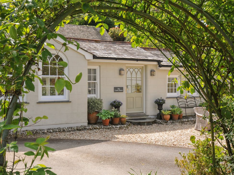 A house with potted plants and a sign at The Coach House at Pendower House Fowey