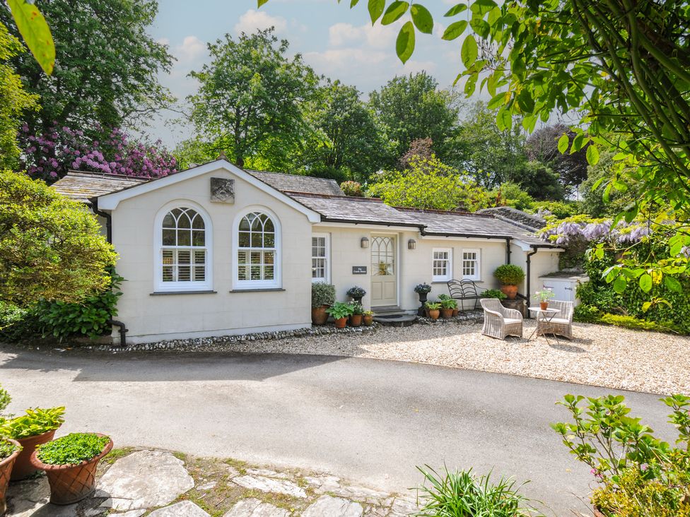 A cottage with potted plants and a gravel driveway at The Coach House at Pendower House Fowey