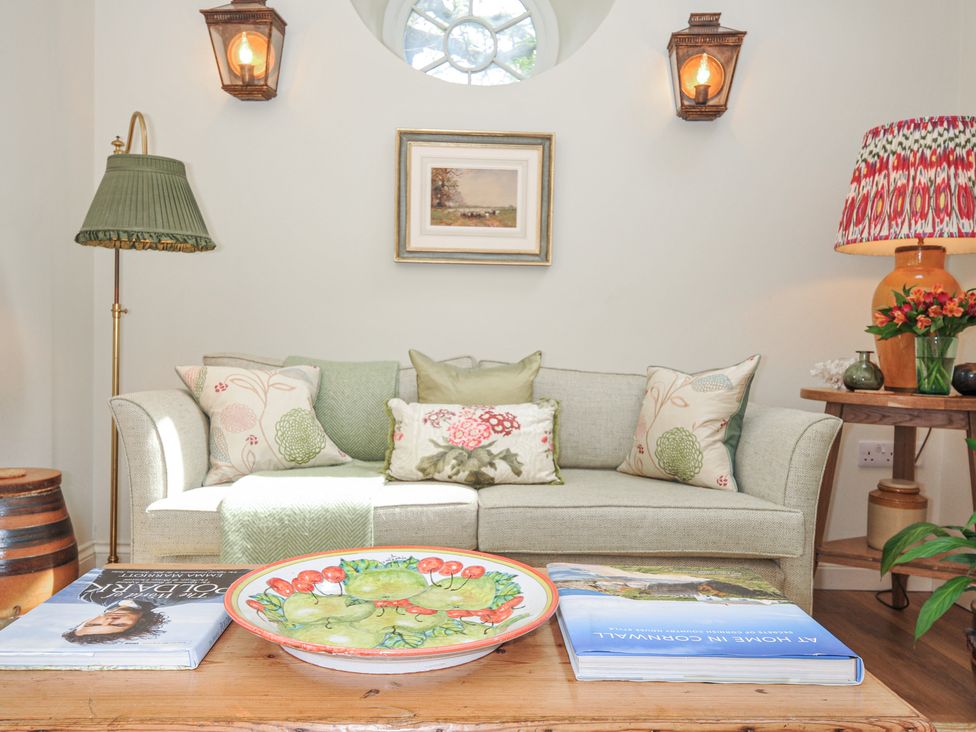 A living room with a sofa, table and lamp at The Coach House at Pendower House Fowey