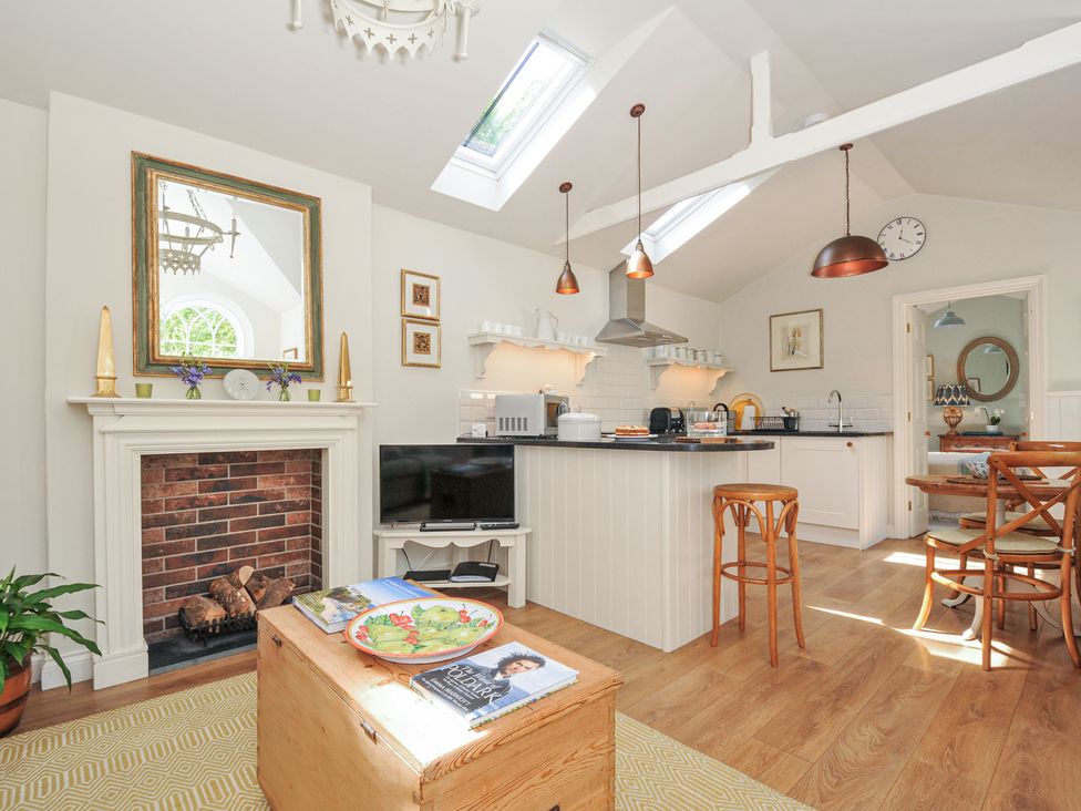 A kitchen with a fireplace and kitchen island at The Coach House at Pendower House in Fowey